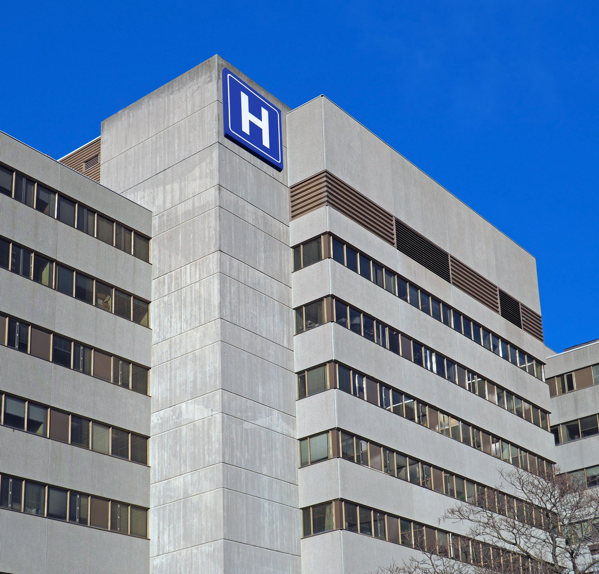 Large concrete building with  H sign for hospital